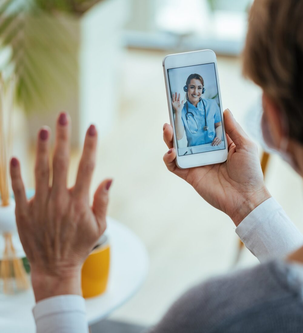 closeup-woman-greeting-her-doctor-while-using-smart-phone-having-video-call-focus-is-female-doctor-touchscreen