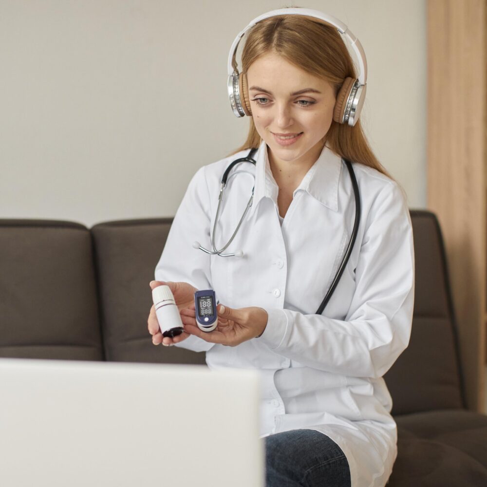 front-view-smiley-covid-recovery-center-female-doctor-with-headphones-holding-oximeter